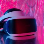 Close-up de um headset moderno de realidade virtual sobre um fundo colorido e refletivo.